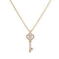 Delicate gold key pendant with heart-shaped bow and crystal pavé detailing on fine chain against cream background.