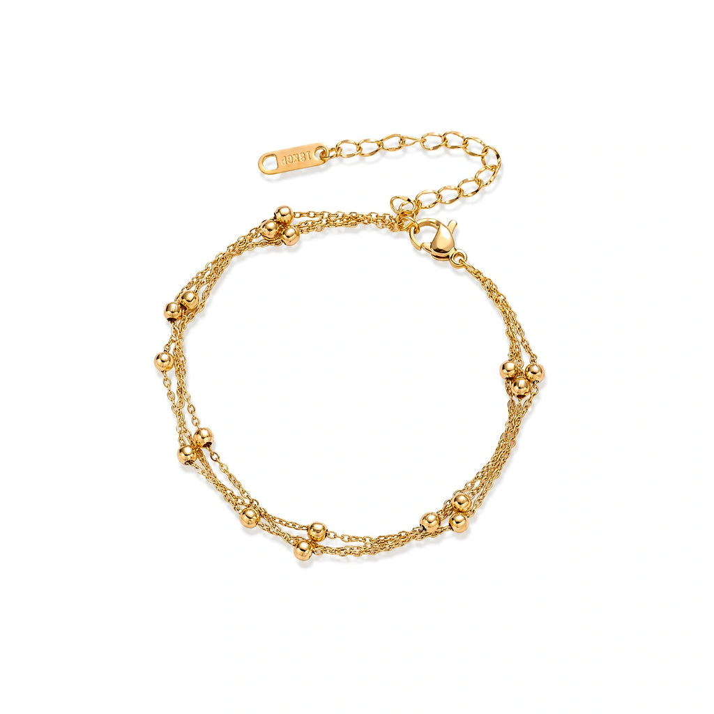Three-strand gold-plated bracelet with clustered ball beads and adjustable clasp on cream background