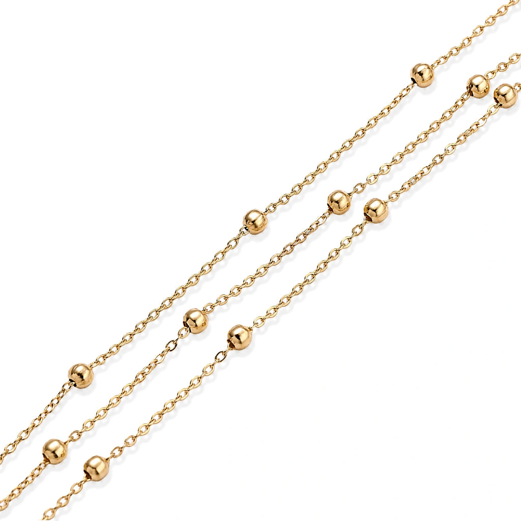 Three-strand gold-plated bracelet with clustered ball beads and adjustable clasp on cream background