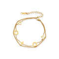 Double-layer gold-plated bracelet with quatrefoil and star charms on cream background, 18K gold finish.