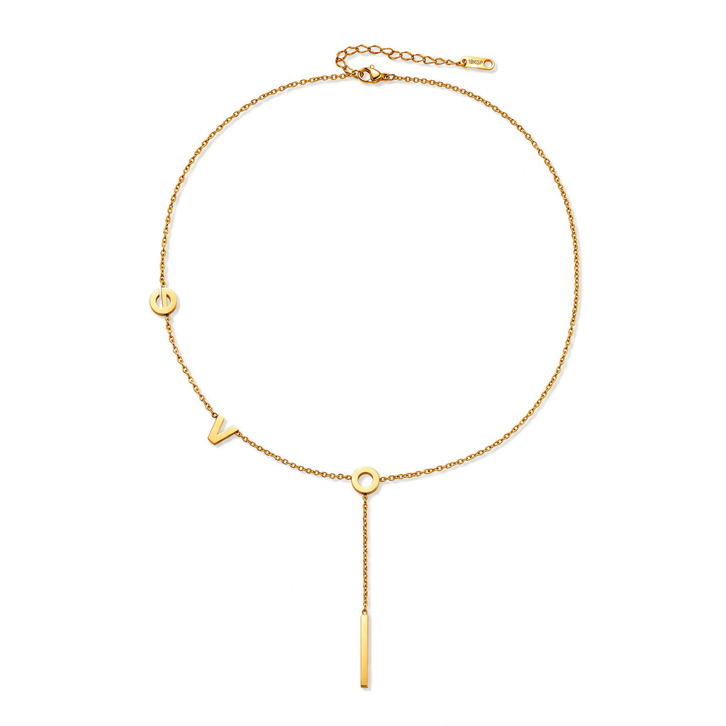 Gold Y-shaped necklace with L-O-V-E letter charms and vertical bar pendant on delicate chain against cream background