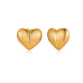 Gold heart-shaped stud earrings with parallel ridged texture on cream background