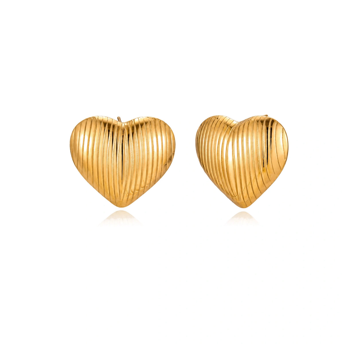 Gold heart-shaped stud earrings with parallel ridged texture on cream background