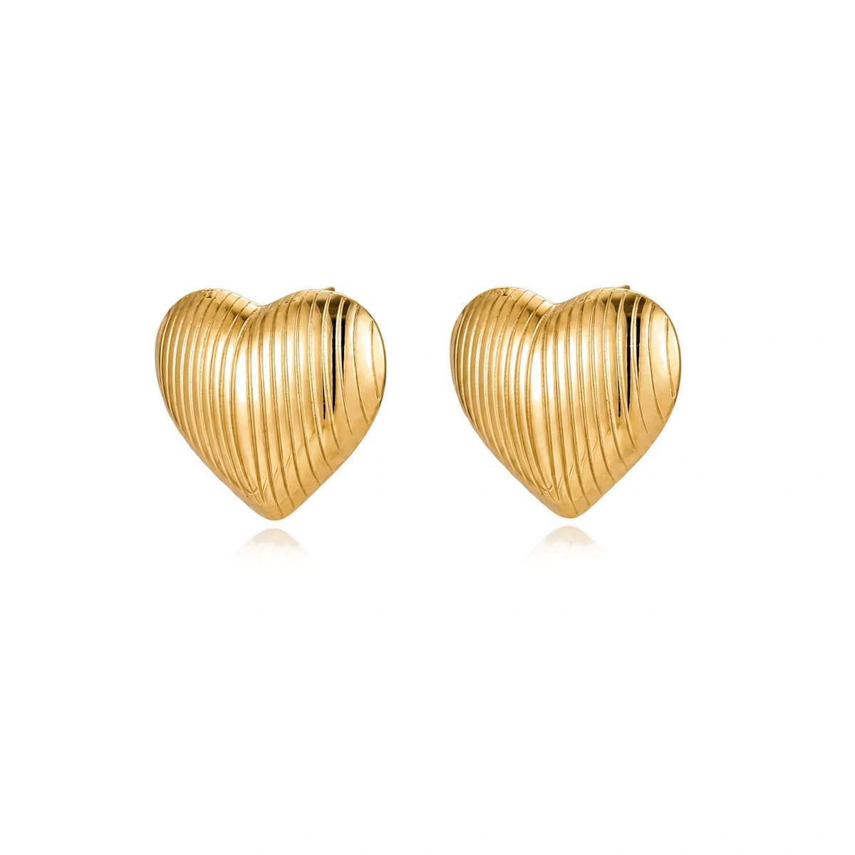 Gold heart-shaped stud earrings with parallel ridged texture on cream background