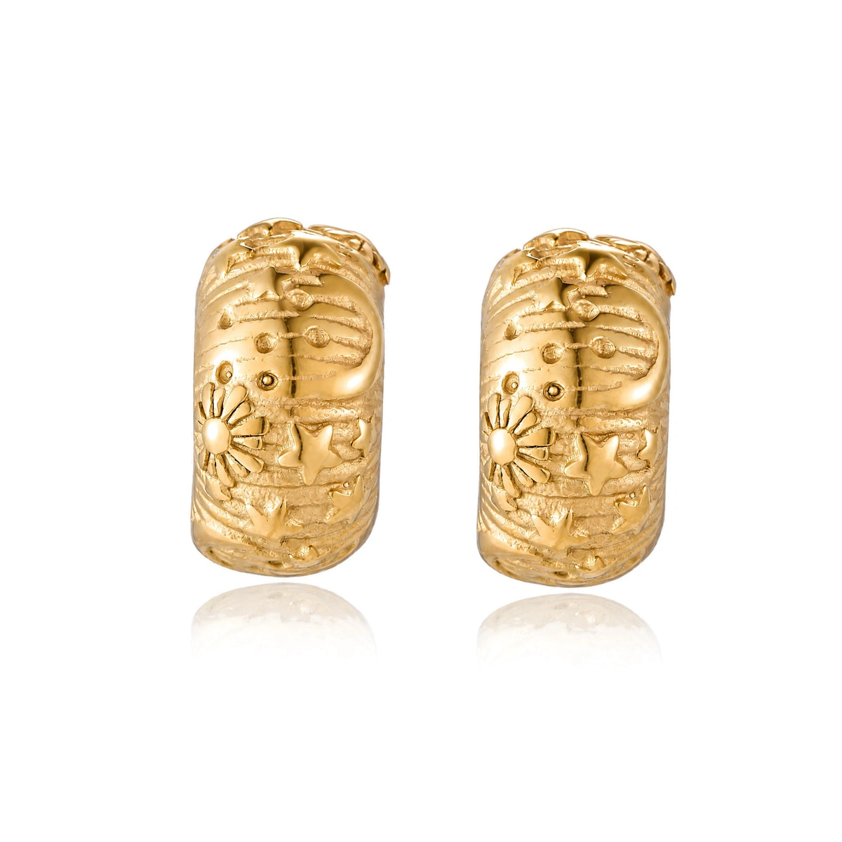Wide gold hoop earrings with embossed stars and sun motifs on cream background, showing dimensional relief details.