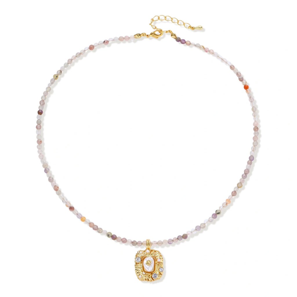 Ornate gold-plated pendant necklace with multicolored gemstone beads in purple, pink and clear tones on white background
