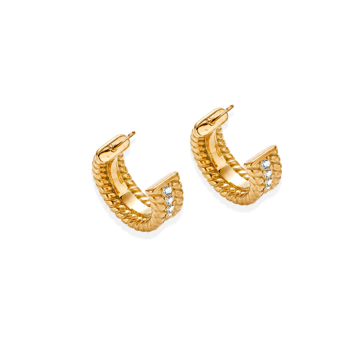 Textured gold huggie hoop earrings with raised ribbed rows creating dimensional sculptural design on cream background