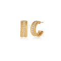 Textured gold huggie hoop earrings with raised ribbed rows creating dimensional sculptural design on cream background