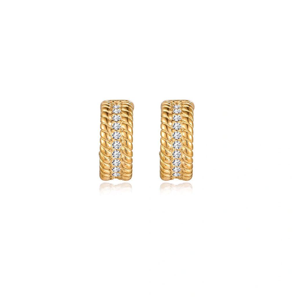 Textured gold huggie hoop earrings with raised ribbed rows creating dimensional sculptural design on cream background