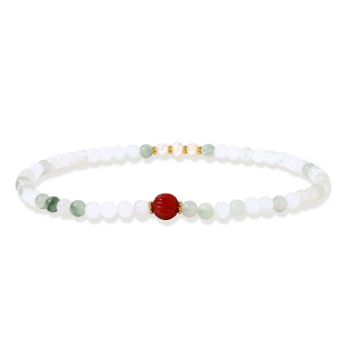 Three layered white beaded bracelets with carved orange agate lotus centerpiece and freshwater pearls on cream background.