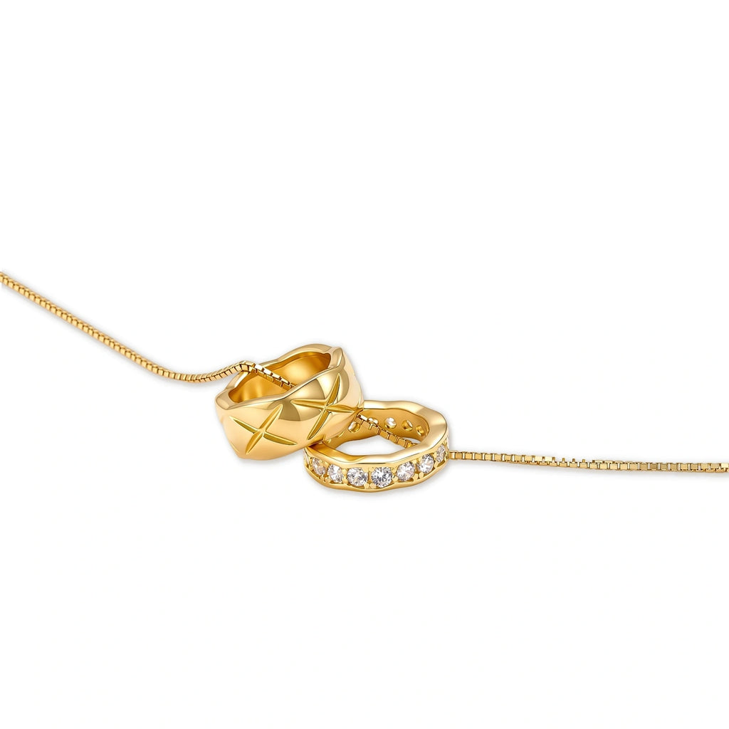 Gold box-chain necklace with two interlocking ring pendants — one star-engraved, one pavé cubic zirconia, 18K gold-plated.