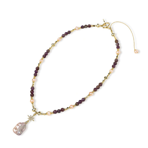 Gold necklace with iridescent baroque pearl pendant, purple amethyst beads, and crystal star charm on cream background