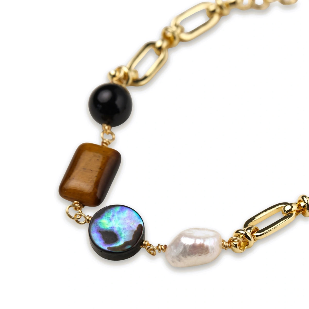 Gold chain bracelet with tiger's eye, obsidian, pearl, and iridescent abalone stones on cream background.